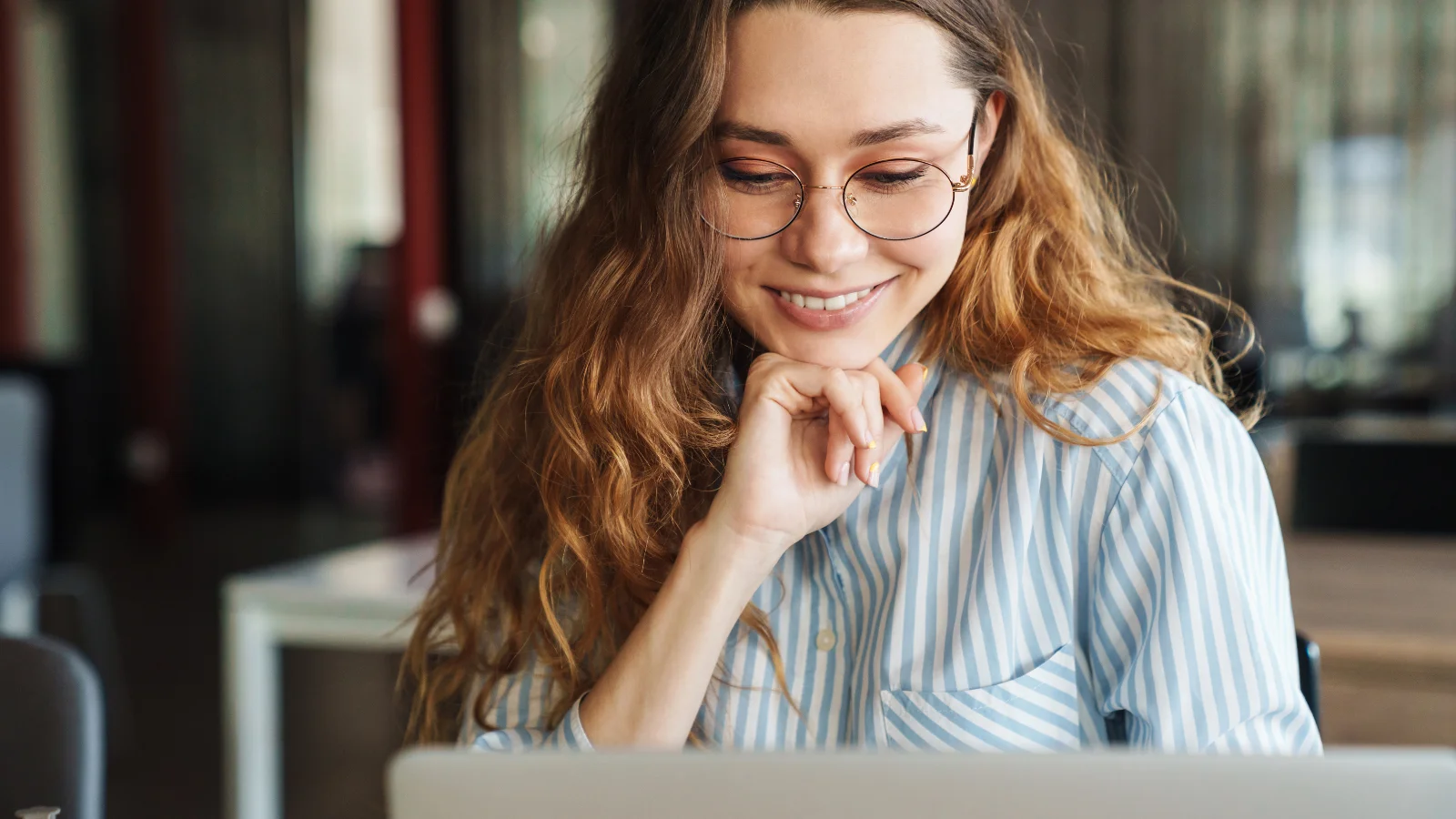 Happy young woman doing her taxes on her laptop