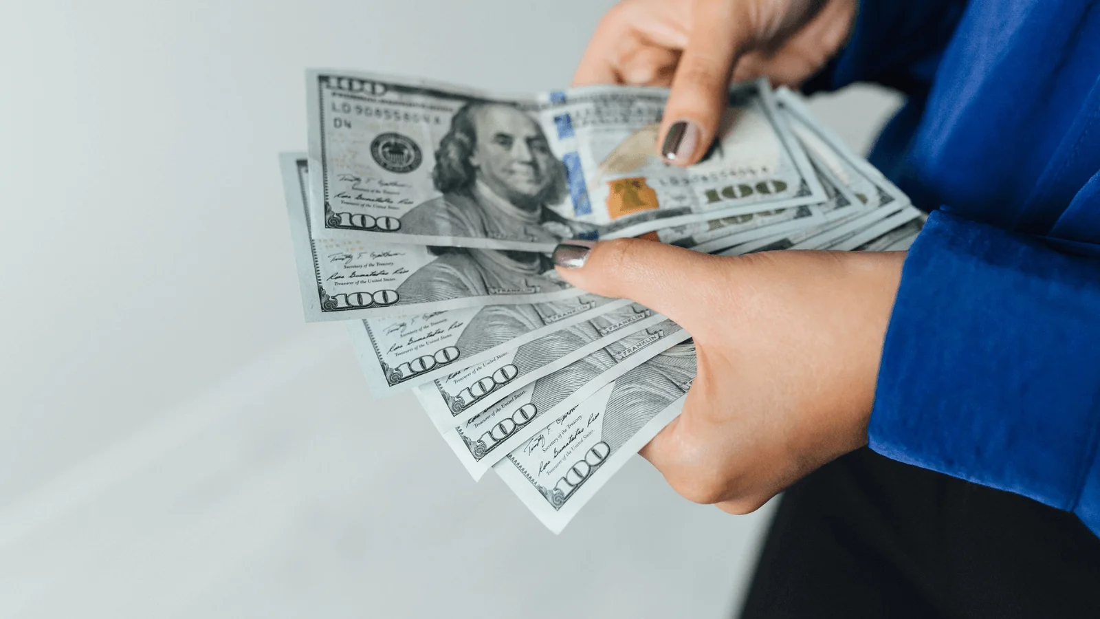 An American woman holding hundreds of dollars in her hand.